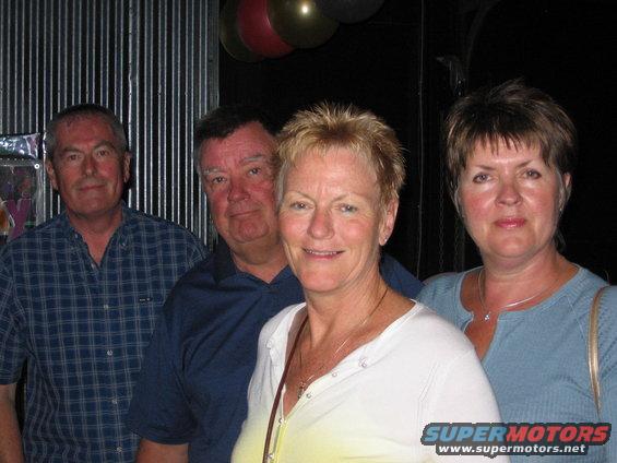 Four adults posing for a photo at a party with balloons in the background