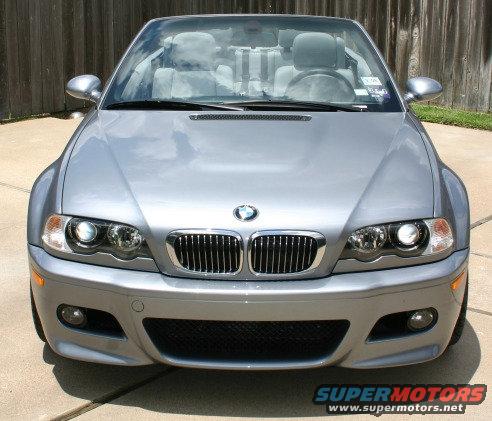 Silver BMW M3 convertible front view, light gray interior, wooden fence background