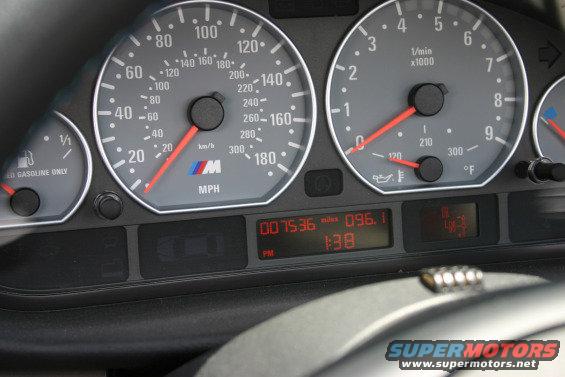Car dashboard with speedometer, tachometer, fuel gauge, and digital display showing mileage and time