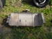 1995 Jeep YJ - A metal component, possibly from a vehicle's undercarriage, rests on a grassy surface next to a tire.