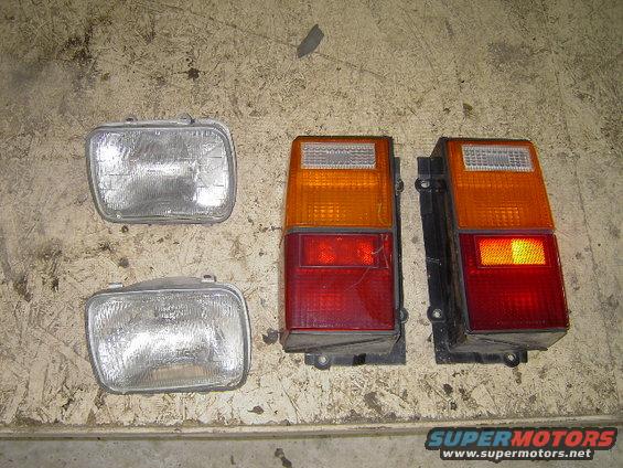 Two rectangular headlights and two Jeep YJ taillights on a wooden surface