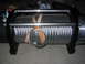 1979 Ford Bronco - A winch with a thick steel cable coiled around its drum, secured with leather straps.