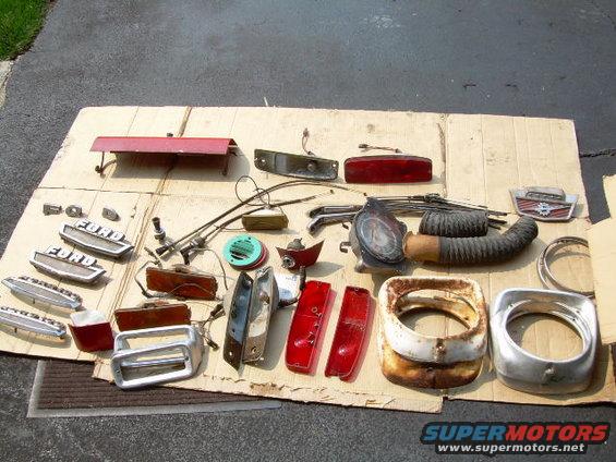 Collection of Ford truck parts including emblems, taillights, grilles, and a headlight bezel