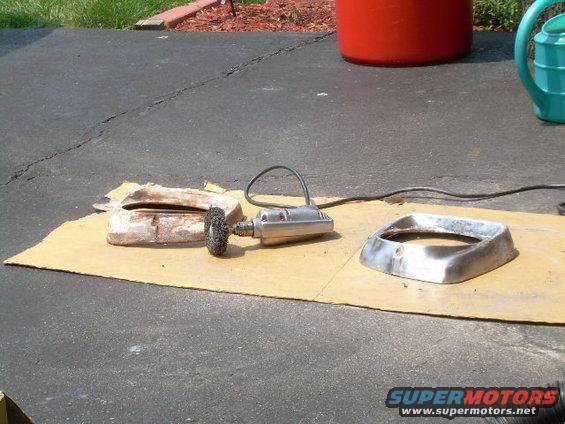 Chrome trim piece and a rusted metal part on cardboard with a rotary tool