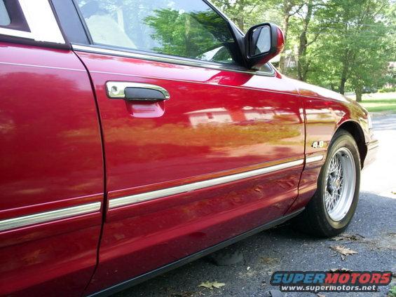 Red 1995 Ford Crown Victoria side view showing door handle and fender badge