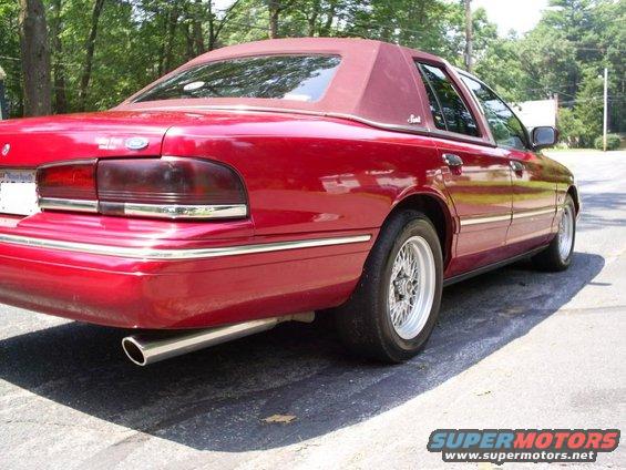 Red sedan with a vinyl top, rear quarter view. It has chrome trim and aftermarket wheels