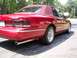 1995 Ford Crown Victoria - This red sedan features a vinyl top and a chrome strip along its side. The rear taillights are tinted.