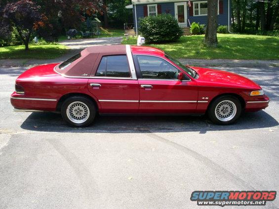Red sedan with a vinyl roof, side view, parked on asphalt