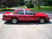 1995 Ford Crown Victoria - A red sedan with a vinyl roof is parked on a street in front of a house.