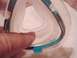 1991 Yugo Cabrio - A close-up view of a medical mask frame, showing its clear plastic and white silicone components with teal accents.
