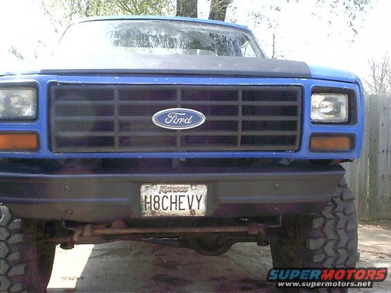 Front view of a blue Ford pickup truck with a black hood accent and a Kansas license plate reading H8CHEVY