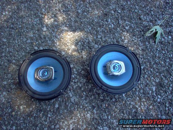 Pair of blue car speakers on gravel