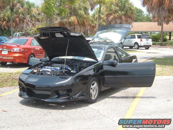 Black sports coupe with hood and driver's door open, showing engine and interior