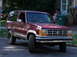 1979 Ford F-250 - Maroon Ford Bronco II drives down a residential street, showing its distinctive grille and body style.