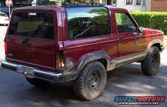 Maroon 1989 Ford Bronco II with a broken taillight and aftermarket wheels parked on asphalt