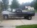 2005 Dodge 1500 - A black and silver crew cab pickup truck is parked on a driveway, with another vehicle visible behind it.