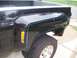 2005 Dodge 1500 - Close-up view of the rear fender of a black pickup truck, distinctive blue pinstripes and an amber marker light.
