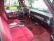 2005 Dodge 1500 - The plush red interior of a classic pickup truck features velour seats and a wood-grain trim on the door panel.