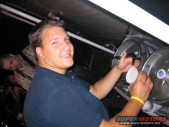 Man pouring drink from keg with two other people in background