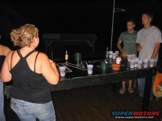 People gathered around a beer pong table with cups and bottles