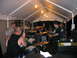 1986 Ford Mustang - A band plays music under a tent, with a drummer in the foreground and other band members visible.