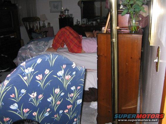 person in orange pants sleeping on a bed in a bedroom