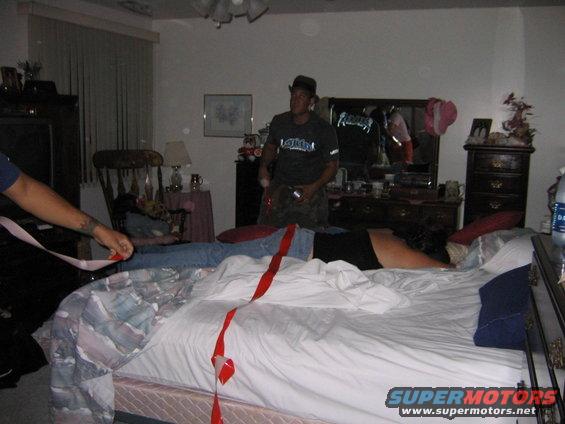 People in a bedroom with red tape on a bed