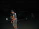 1986 Ford Mustang - A dark SUV is parked on a street at night, with two people visible nearby.