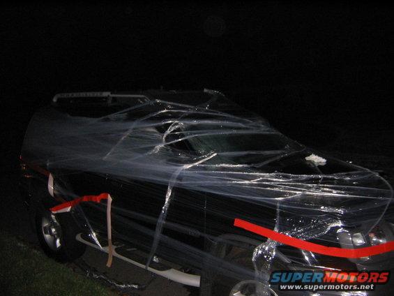 Black SUV covered in plastic wrap with red tape