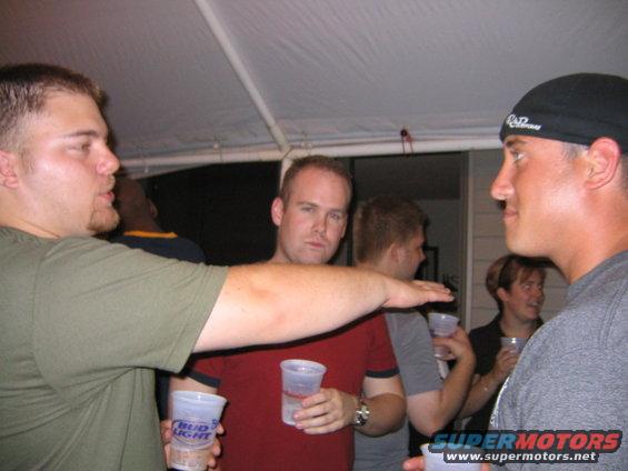 People holding drinks at an outdoor party under a canopy