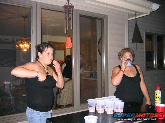 Two women at a table with cups set up for beer pong