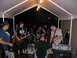 1986 Ford Mustang - A band performs music outdoors under a white canopy, with instruments and equipment set up.