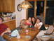 1986 Ford Mustang - Three women are gathered around a wooden dining table, enjoying drinks and conversation.