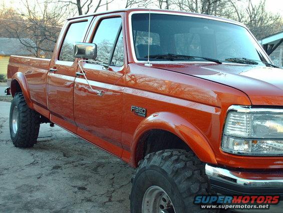 Orange 1991 Ford F-350 pickup truck, four-door cab, lifted suspension, large tires