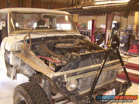 White pickup truck front view, hood open, engine exposed, grille visible