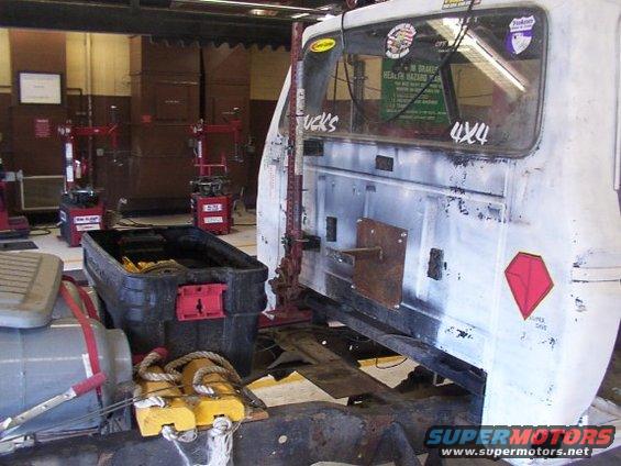 Truck cab on a lift with tools and tire machines in background. Some stickers on the rear window