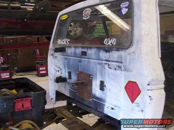 Rear of white vehicle with "BUCKS" and "4x4" stickers, spare tire visible inside