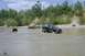 2005 Yamaha GRIZZLY 660 - Multiple off-road vehicles navigate a muddy terrain, with a black pickup truck prominently stuck in the mire.