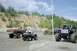 2005 Yamaha GRIZZLY 660 - A quad bike and rider navigate a dirt track with several trucks in the background, suggesting an off-road event.