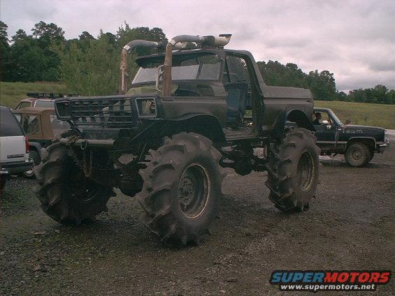 Monster truck with massive mud tires, snorkel exhaust, and open doors