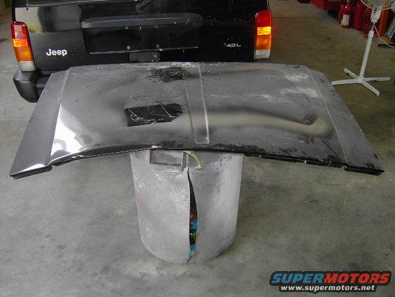 Black Jeep Cherokee XJ rear with hood removed and resting on a stand. The hood is also black
