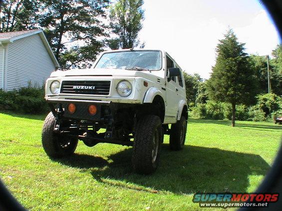 White Suzuki Samurai with aftermarket bumper and large tires