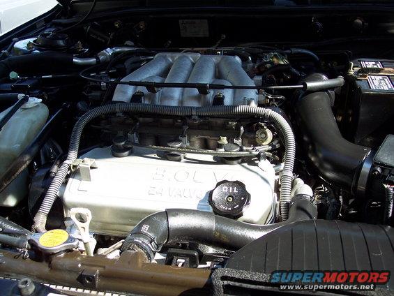 Engine bay of a 1995 Ford Probe, showing the V6 24-valve engine with silver intake manifold and white valve cover