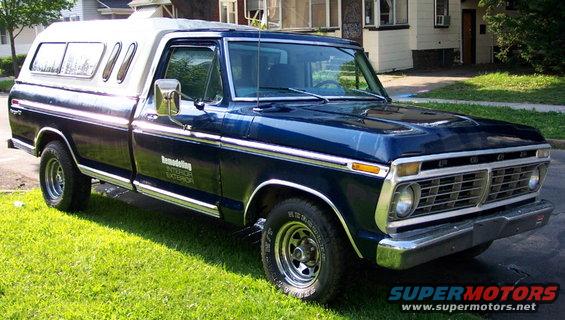 Dark blue Ford F-150 pickup truck with a white camper shell, parked on grass. Text on the door reads 'Remodeling Interior Exterior'