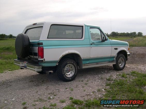 1994 Ford Bronco parked on a gravel road, rear view with spare tire mounted on the back