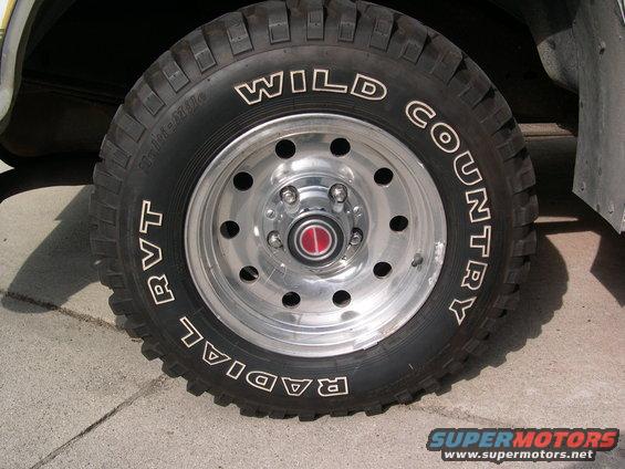 Close-up of a Wild Country Radial RVT tire on a chrome wheel with a red center cap