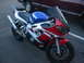 2001 Yamaha R1 - A red, white, and blue 2001 Yamaha R1 motorcycle is shown from a 3q front angle, with a portion of a truck visible in the background.