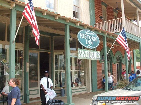 Historic inn and antique shop with American flags. A man in a uniform stands by the entrance