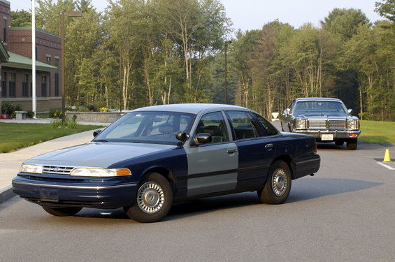 Two-tone sedan parked on asphalt, another car behind it
