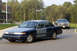1978 Dodge Monaco - A dark blue and gray sedan is parked on a road with a building and trees in the background.